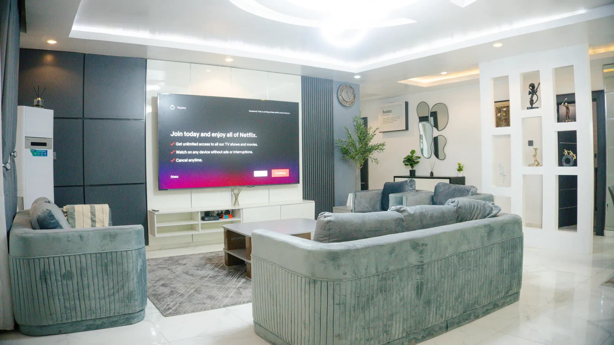 Spacious living room with velvet sofas, statement TV wall and LED cove ceiling lighting