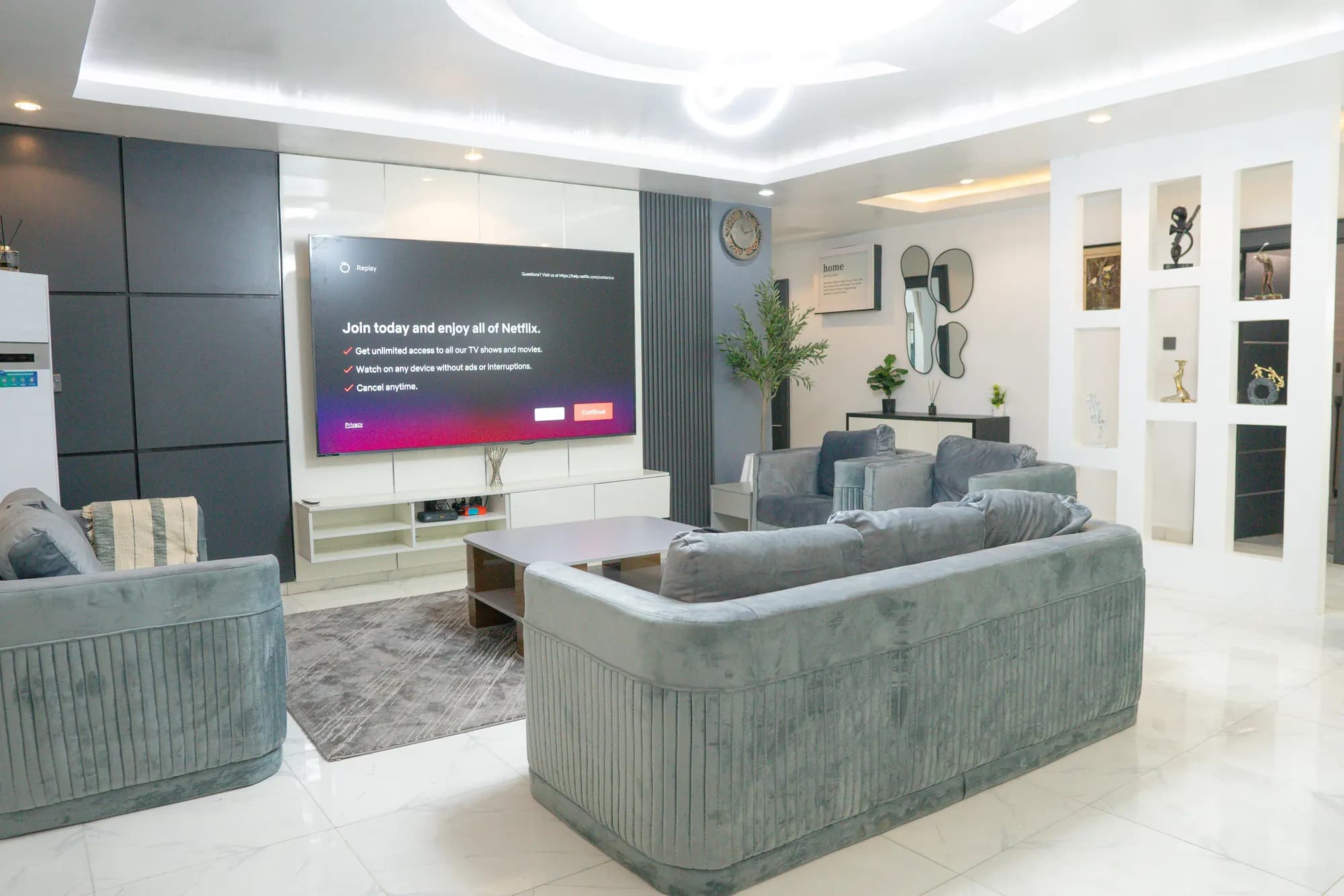 Elegant living room with grey velvet seating, wall-mounted TV and sculptural display partition
