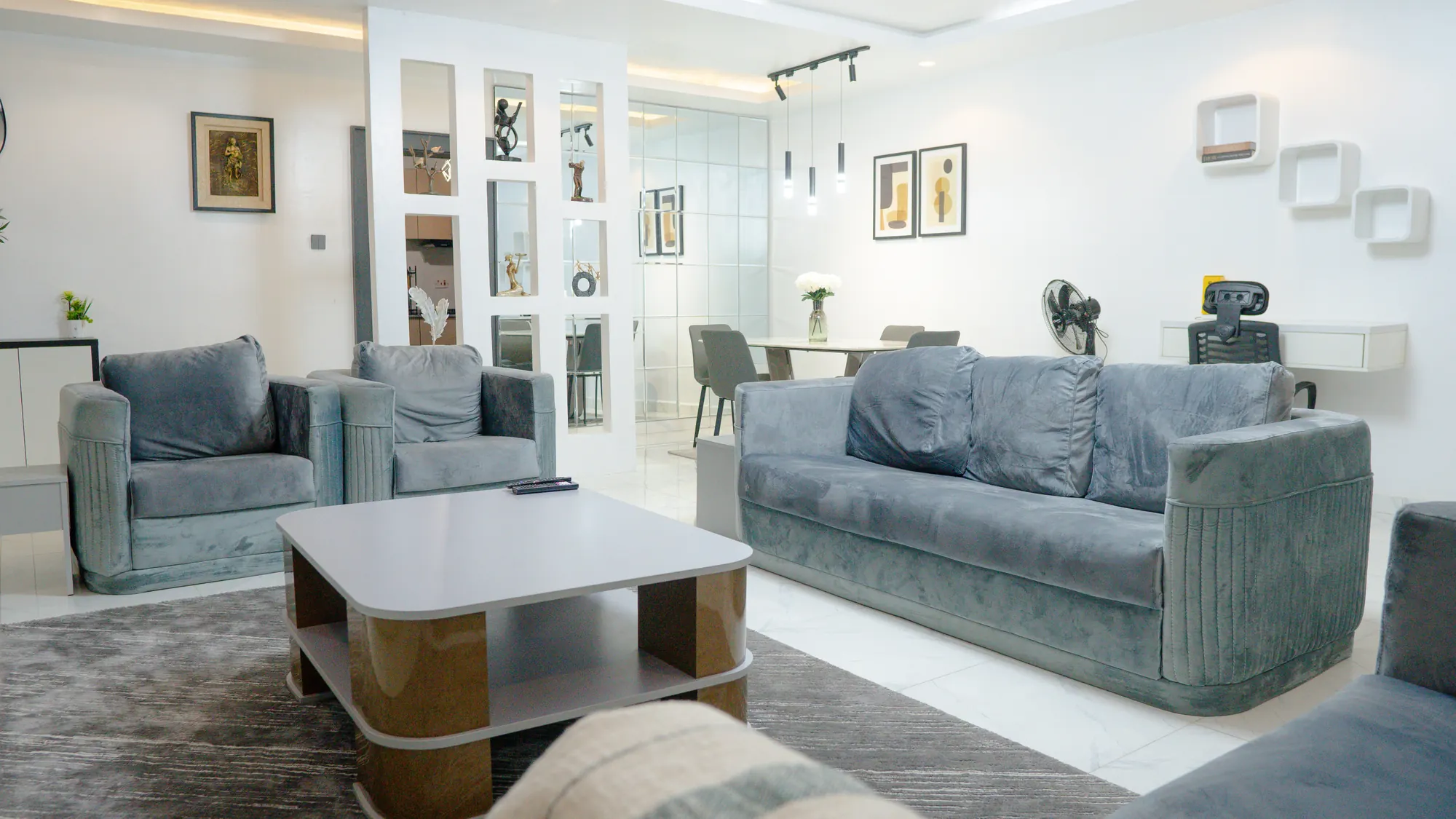 Open-plan living and dining area with velvet seating, art and a mirrored feature wall