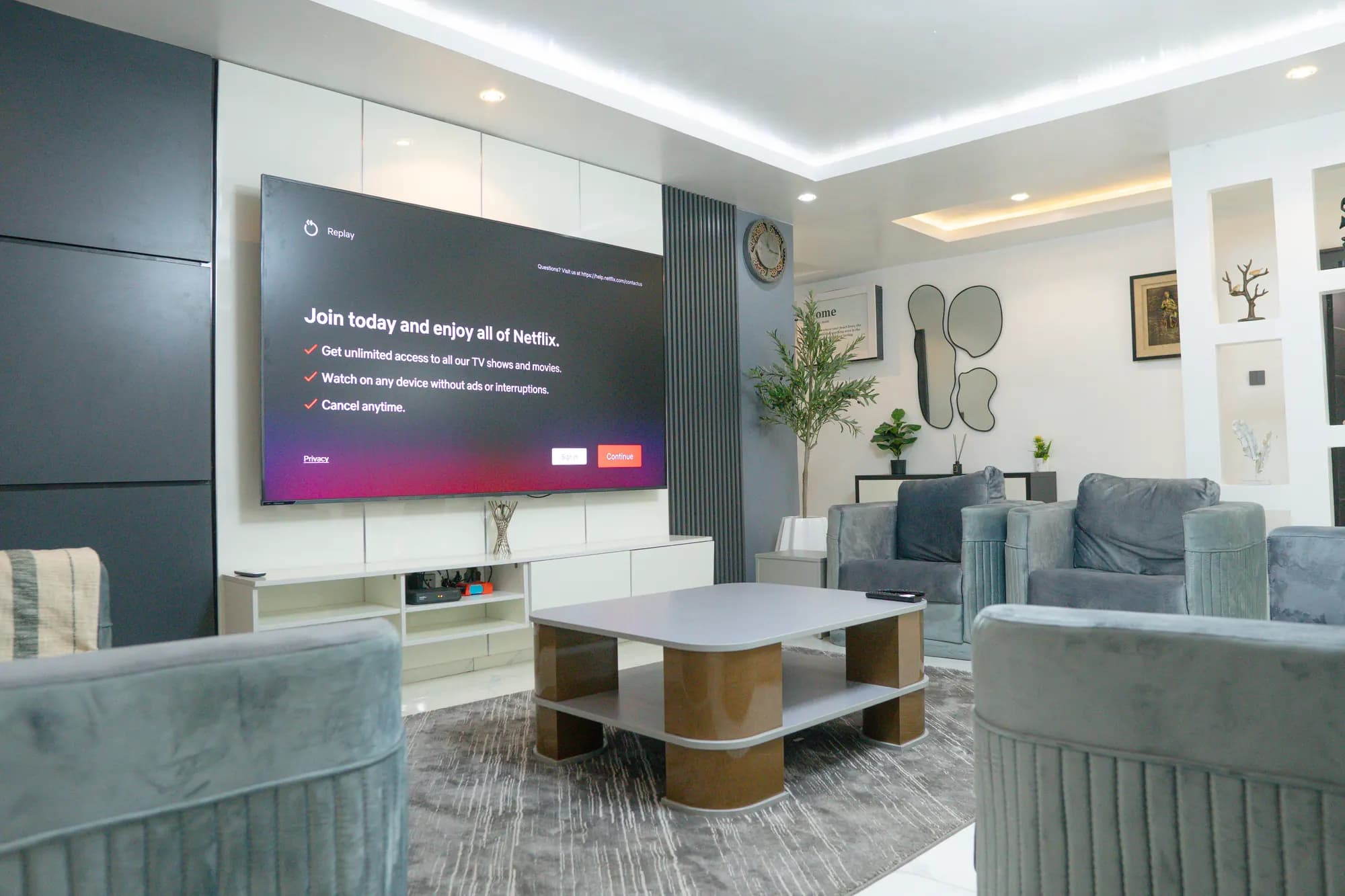 Low view across a designer coffee table to a plush living area with a statement TV wall