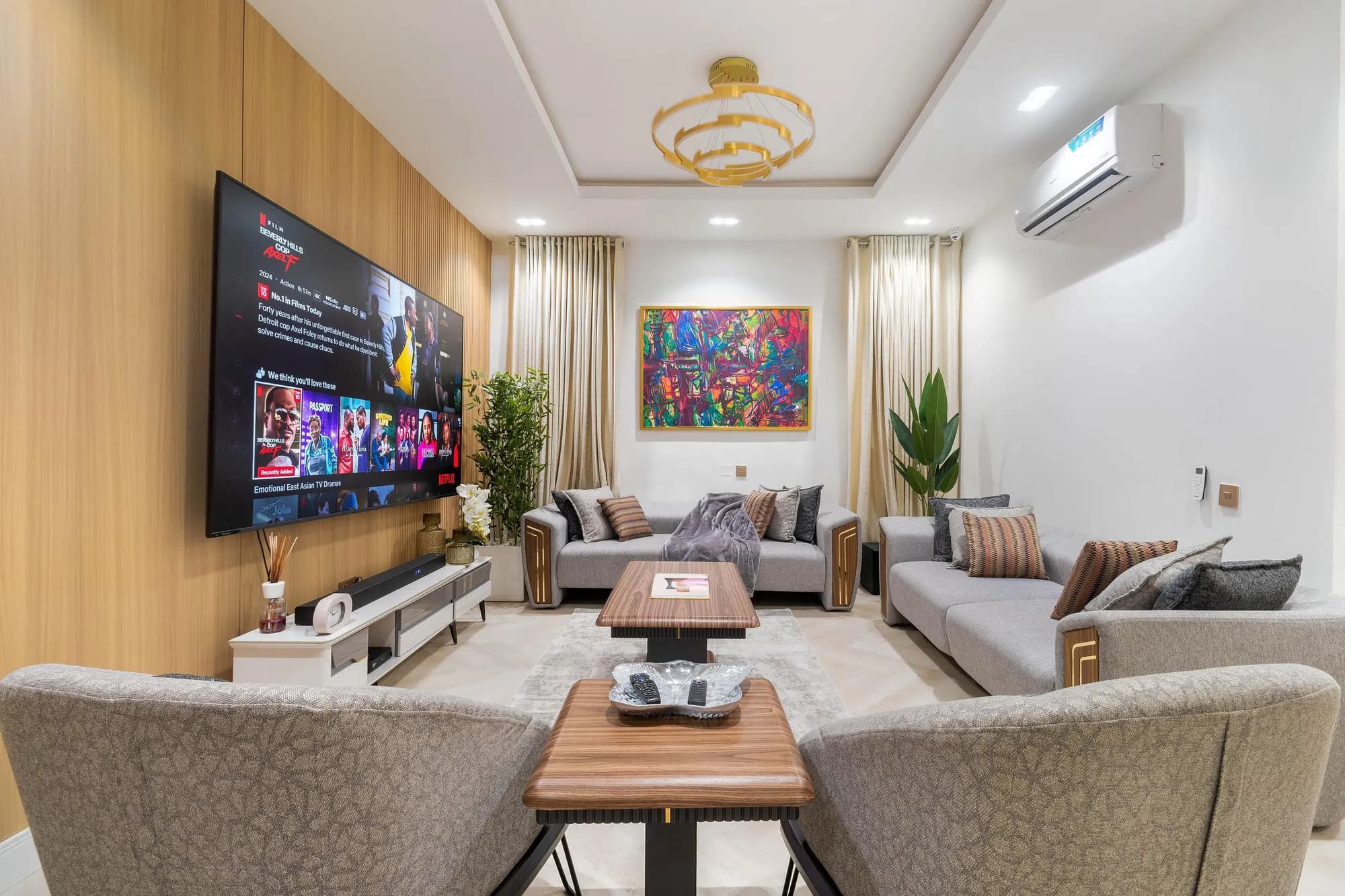 Symmetrical living room with oak TV wall, gold chandelier and abstract canvas