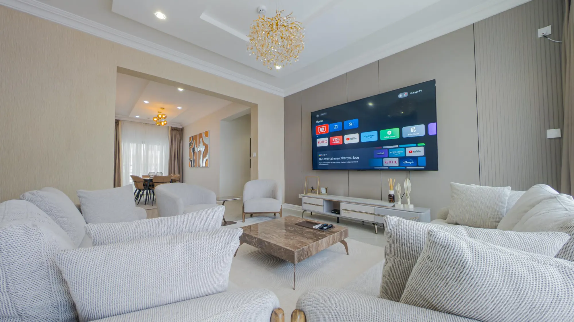Sunlit living room with a gold chandelier and an archway opening to the dining area