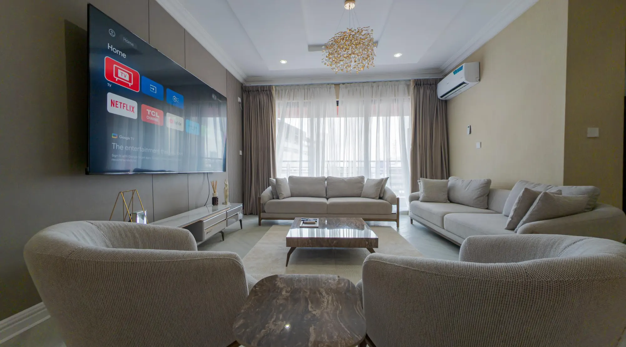 Living room with smart TV, facing cream sofas and a marble coffee table