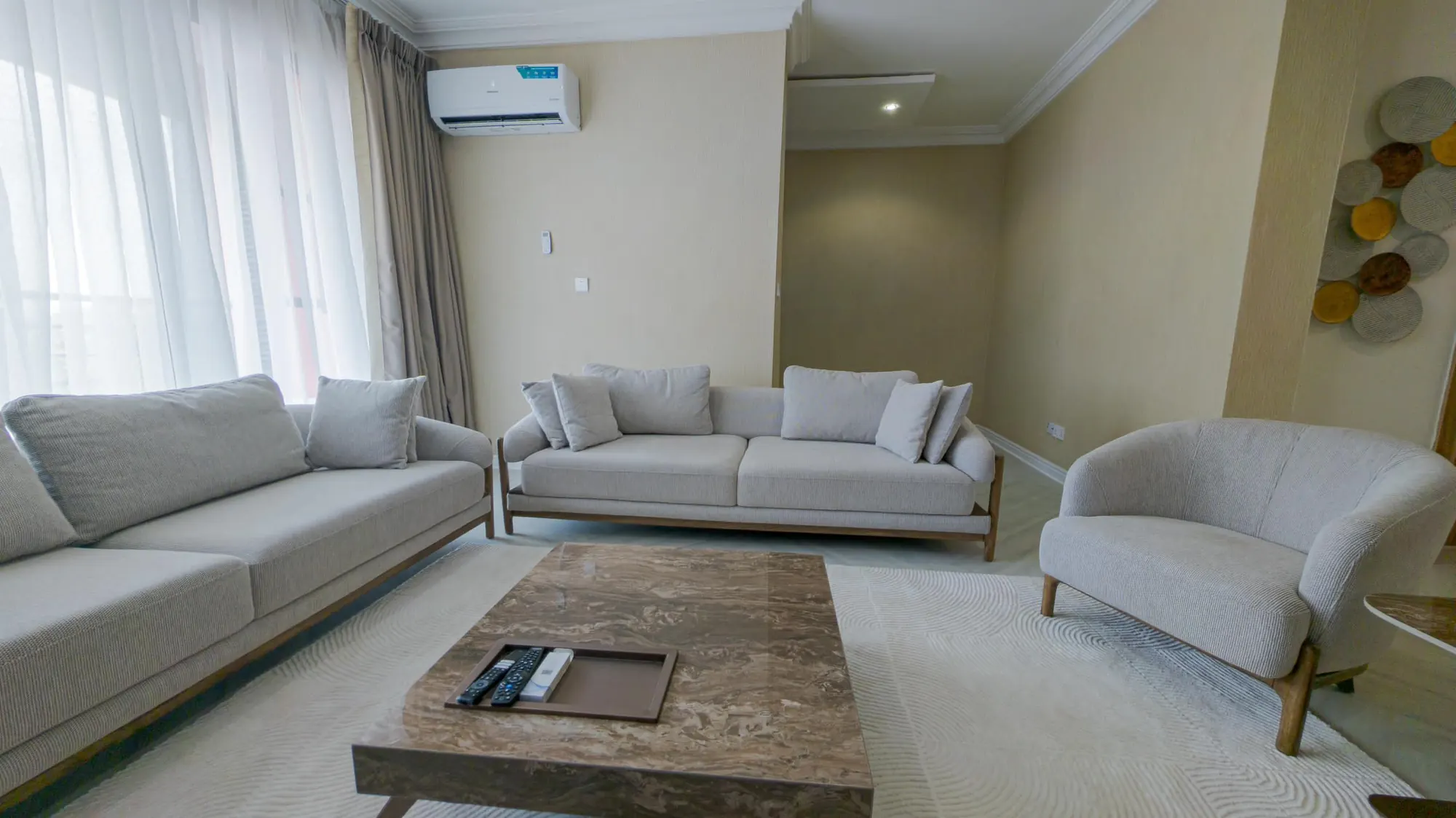 Living area with cream sofas, marble coffee table and gold disc wall decor