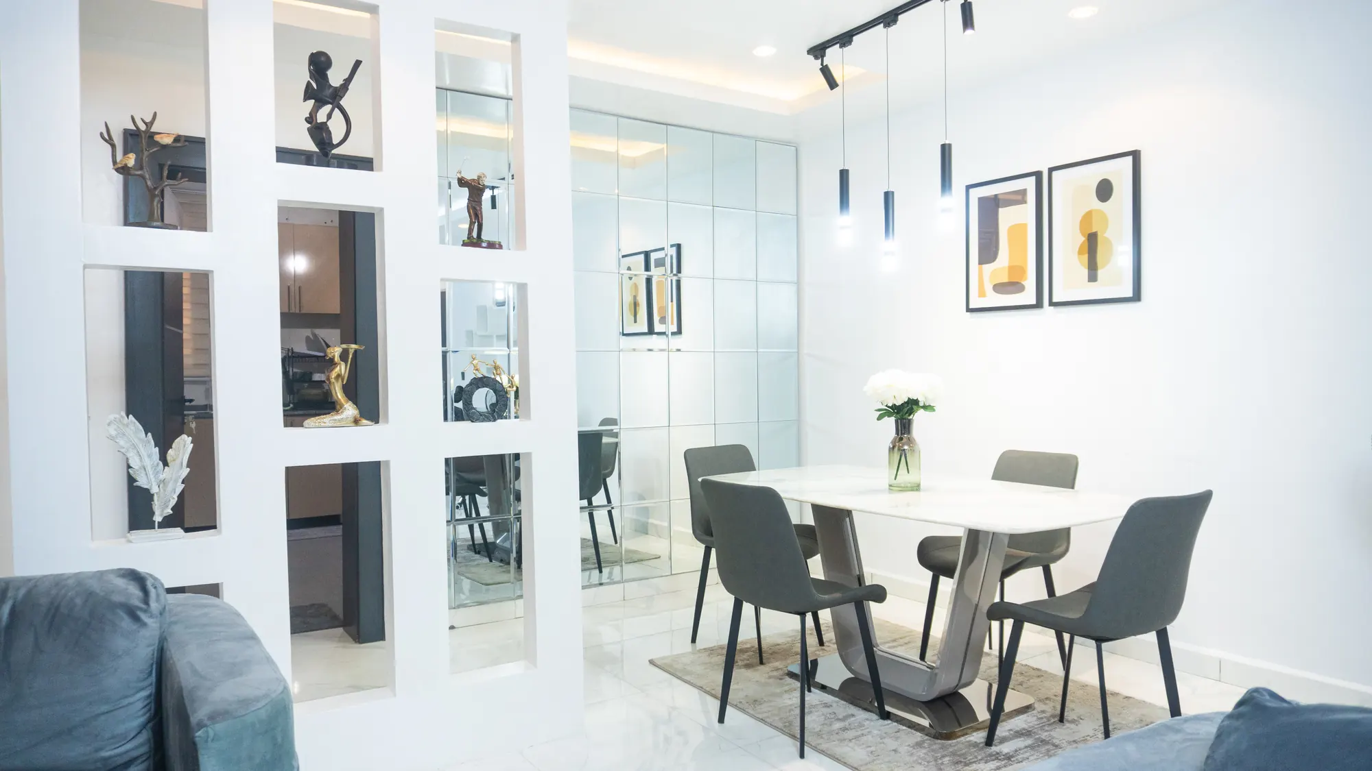 Contemporary dining area with a marble-top table, grey chairs, pendant lights and mirrored wall