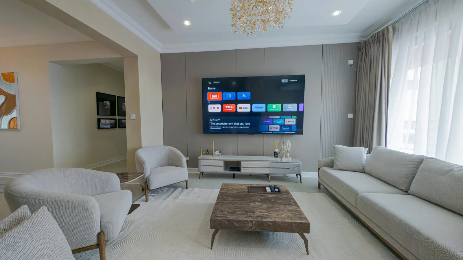Living room with a smart TV, marble coffee table and crystal chandelier at MJ's Haven Victoria Island