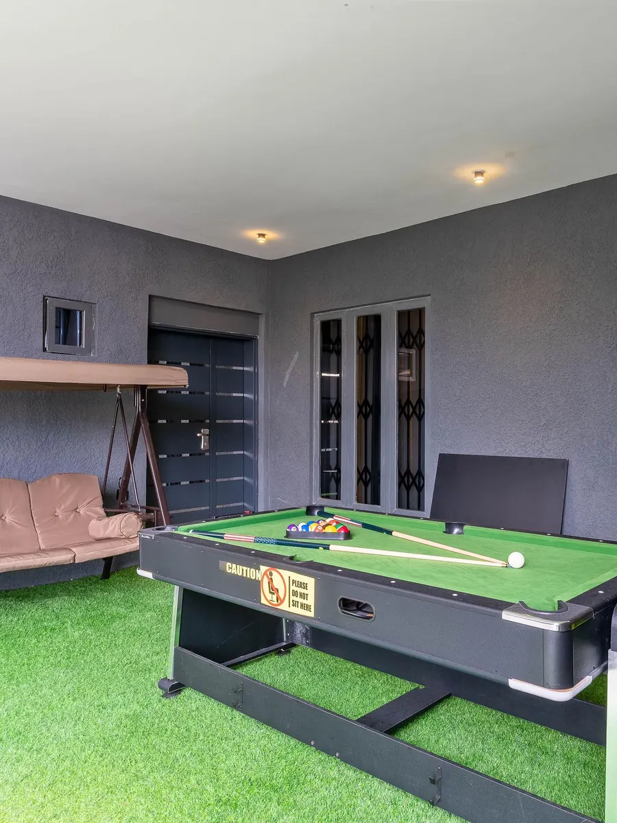Covered games terrace with a pool table and garden swing